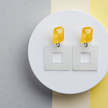 Load image into Gallery viewer, NINIWEAR sunshine yellow handcrafted earrings on grey and yellow background
