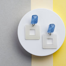 Load image into Gallery viewer, NINIWEAR blue crystal with white square handcrafted earrings on grey and yellow background
